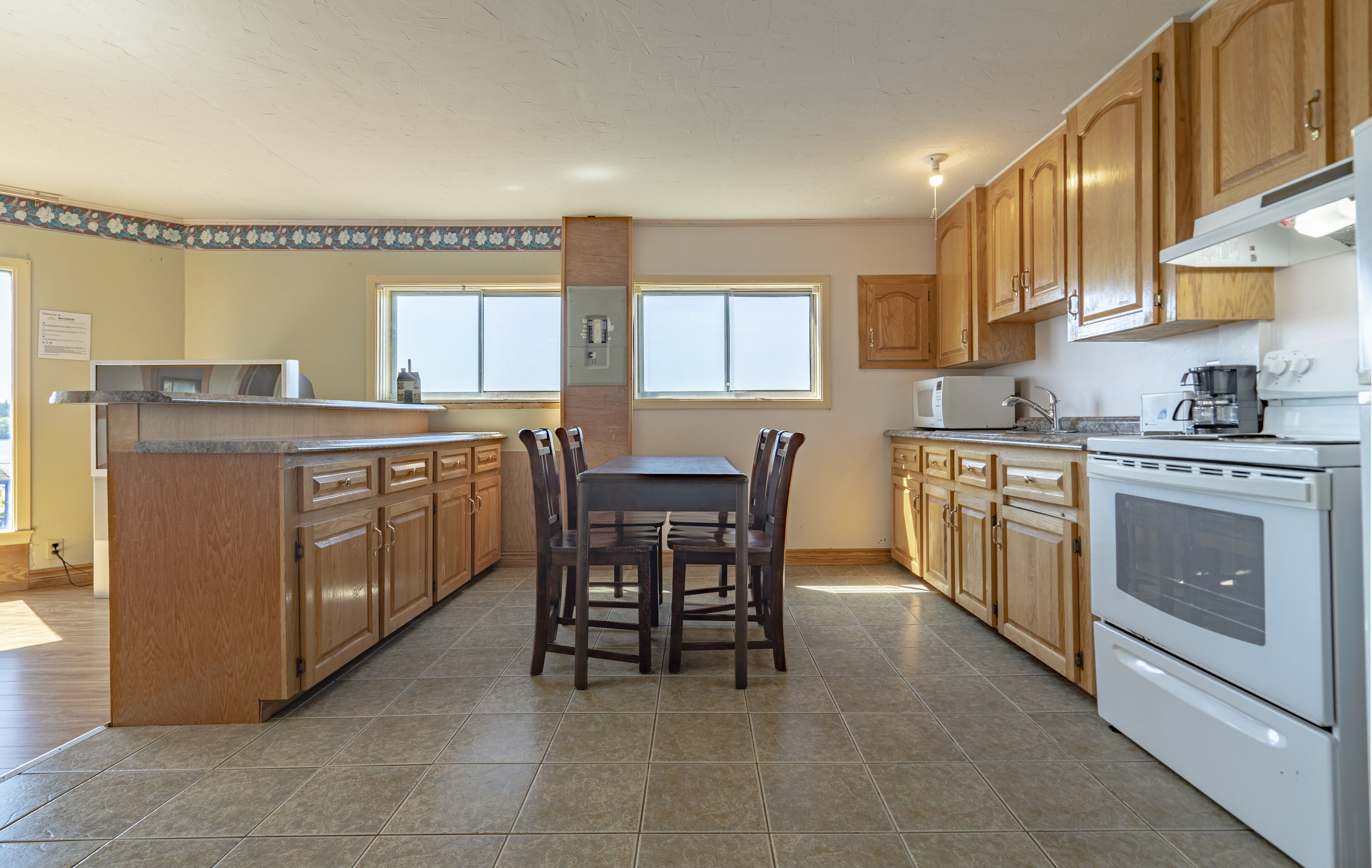 A spacious kitchen with wooden cabinets, a central island with seating, and modern appliances.