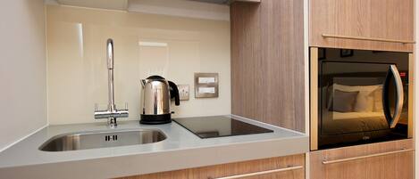 A modern kitchen with a stainless steel sink, a kettle, and a built-in oven.