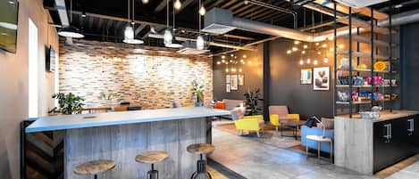 A modern bar area with a wooden counter, bar stools, and pendant lighting.