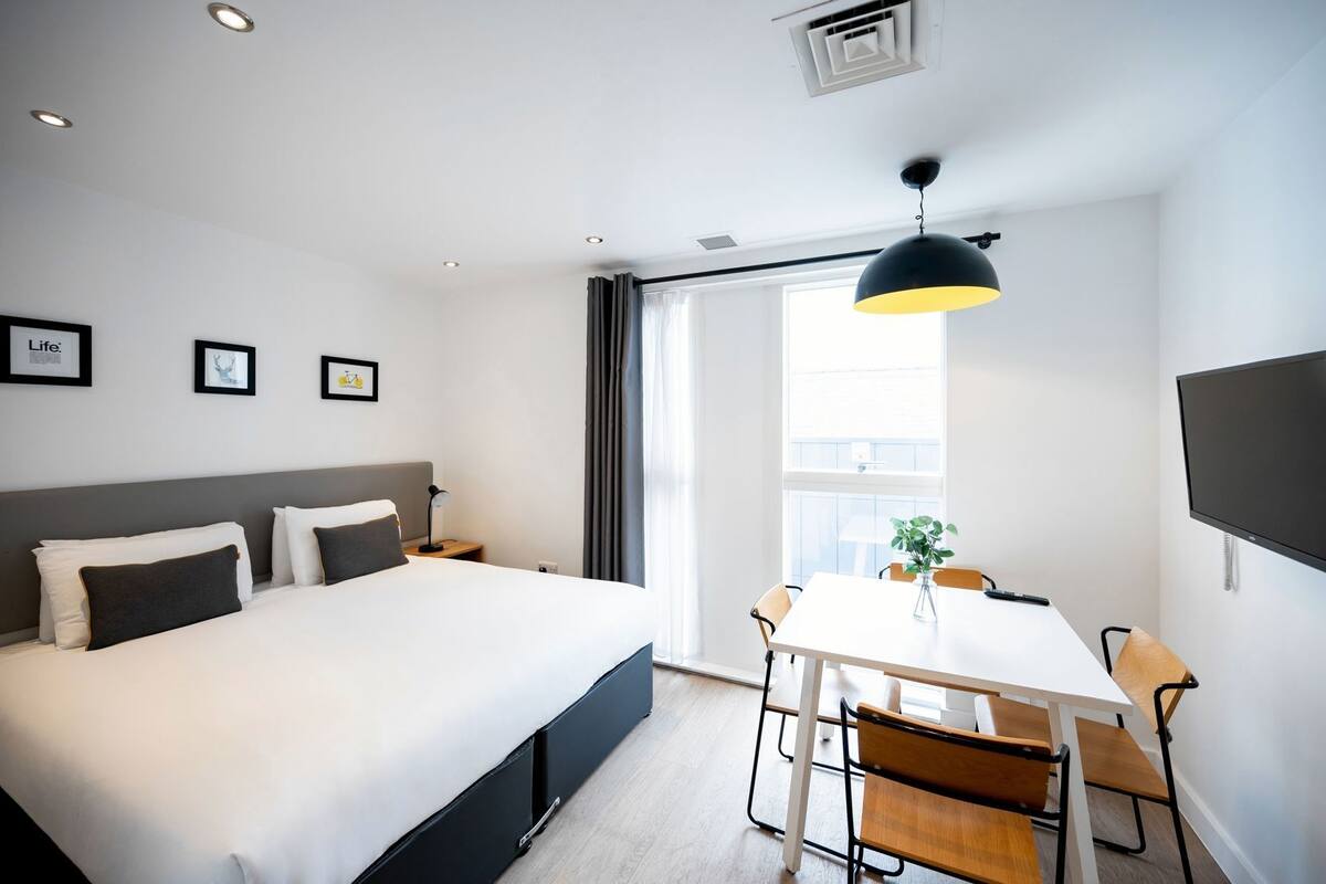 A modern hotel room with a large bed, a desk, and a TV.