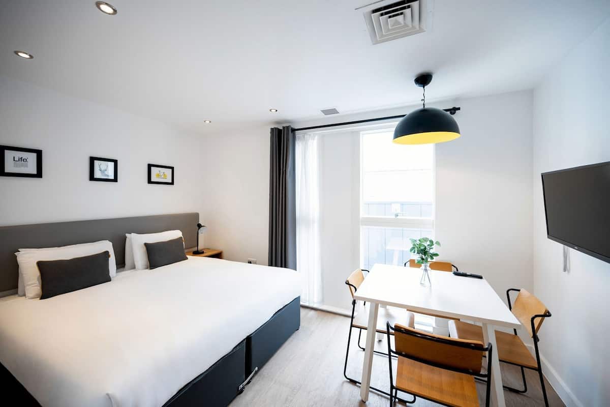 Une chambre dâhĂŽtel moderne avec un grand lit, un bureau et une tĂ©lĂ©vision.