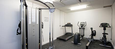 A gym with a treadmill, elliptical, and weight machine.