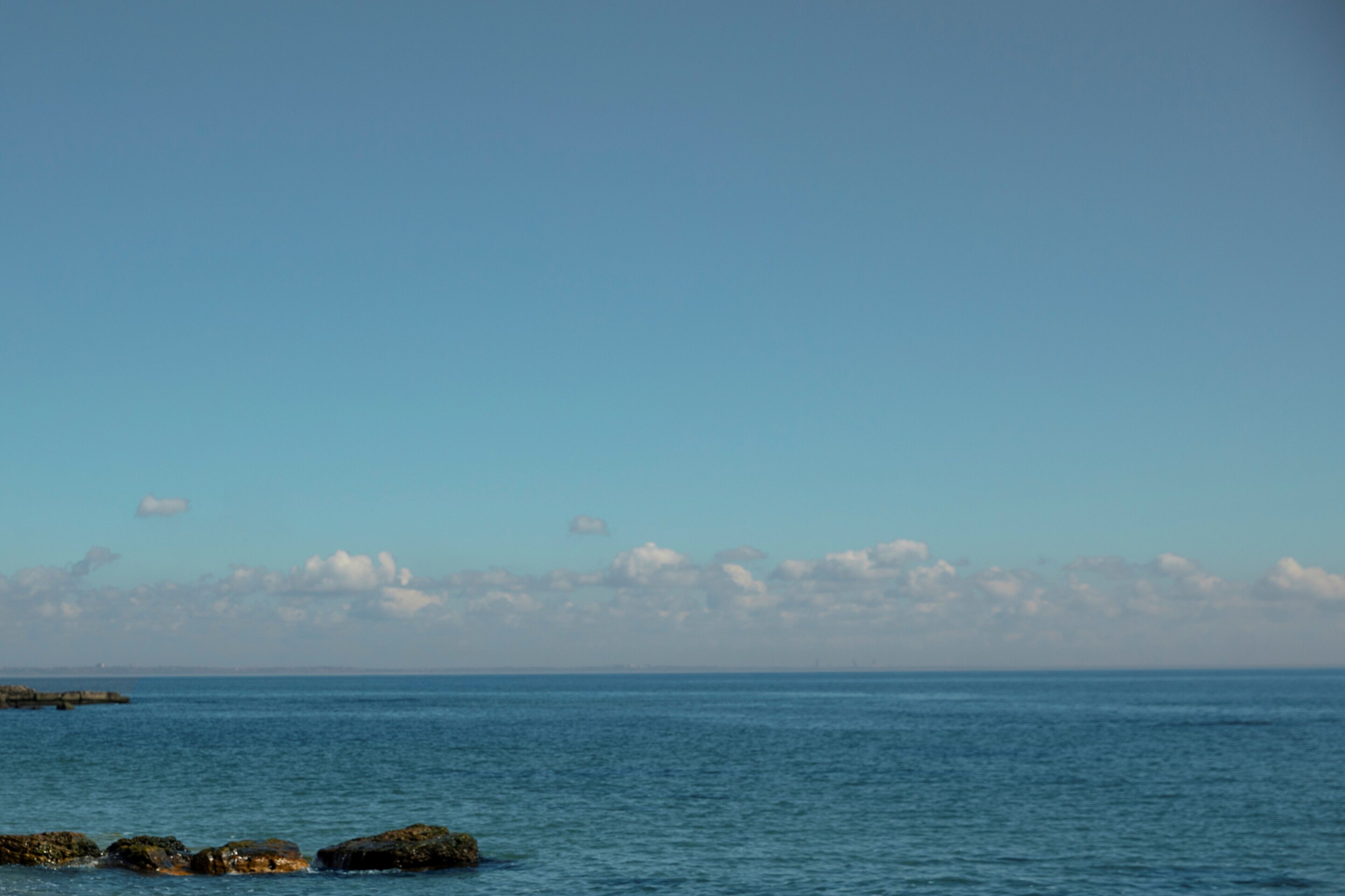 A coastal view with calm sea and rocky shoreline.