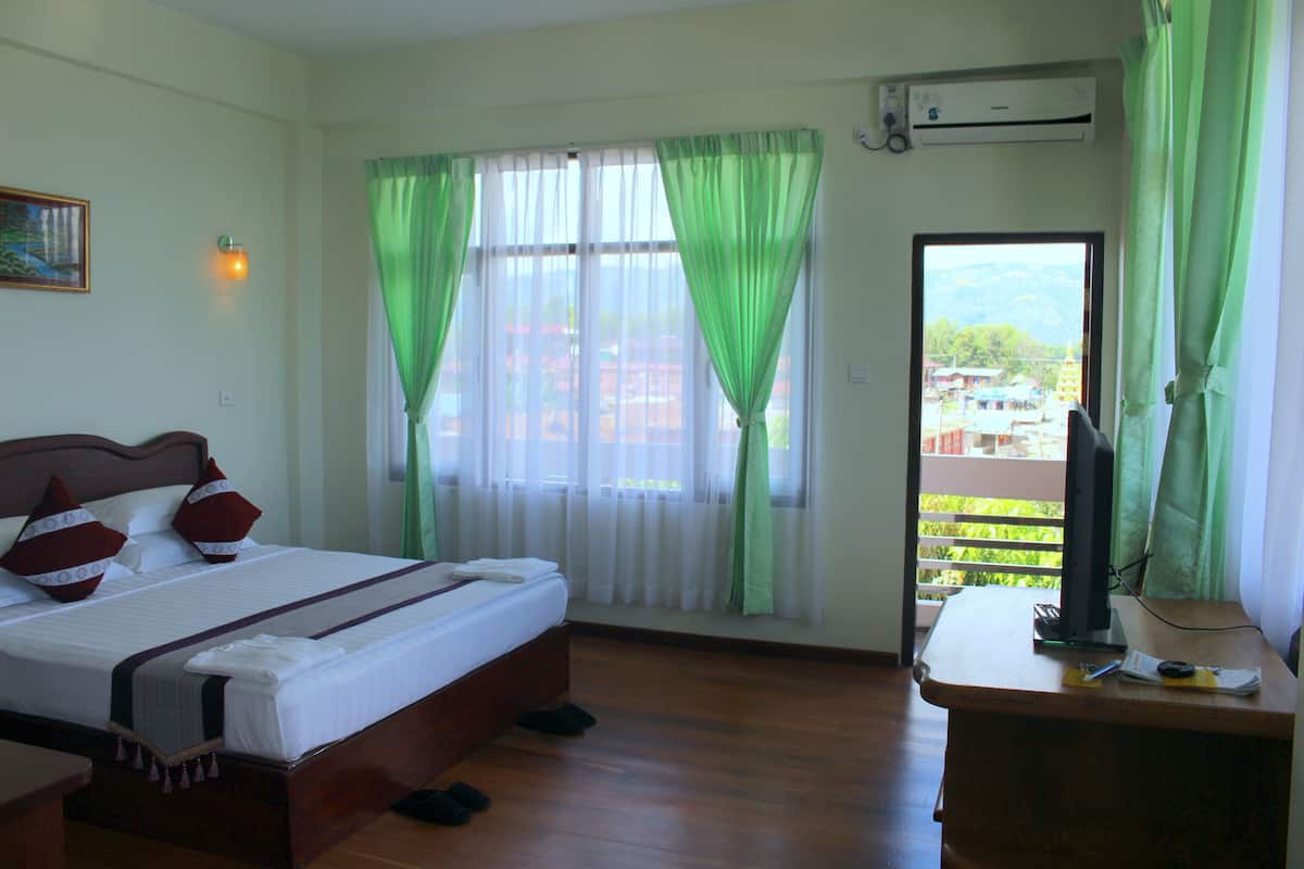 A hotel room with a bed, a desk, and a view of the outside.