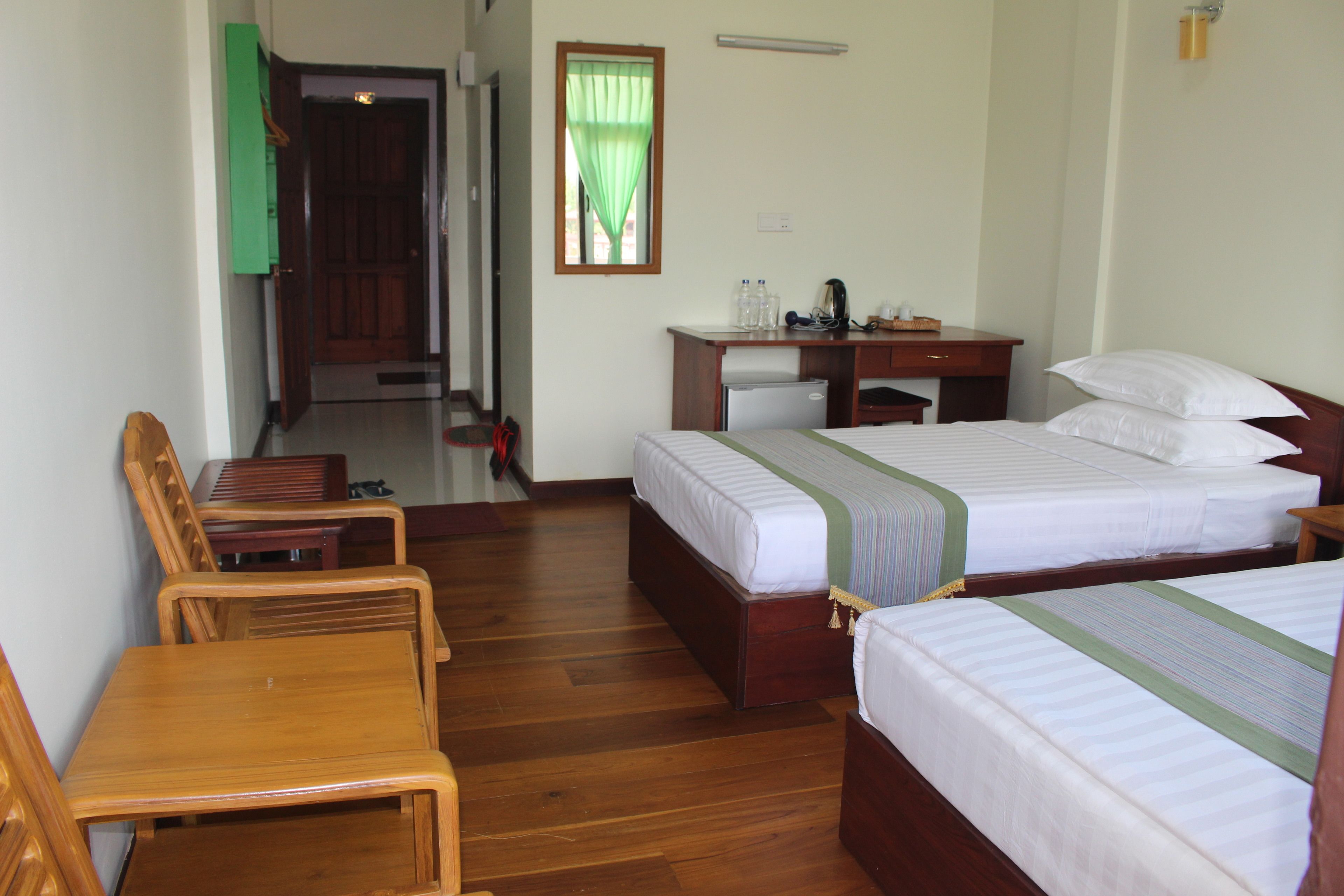 A hotel room with two beds, a desk, and a chair.