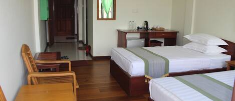 A hotel room with two beds, a desk, and a chair.