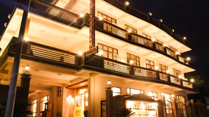 Ein mehrstöckiges Hotel mit einem markanten Eingangsbereich, Balkonen und beleuchteter Beschilderung.