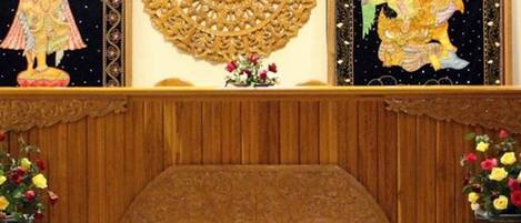 A wooden wall with intricate carvings and two vases with flowers.