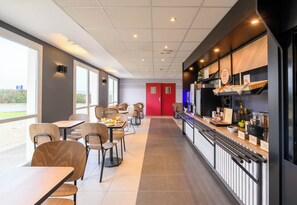 A modern cafe with a long counter, chairs, and tables. - B&B HOTEL Compiègne Thourotte (Thourotte)