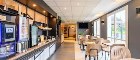 A modern cafe with a long counter, seating area, and large windows.