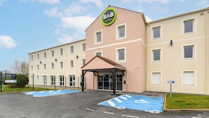 Un hotel B&B con entrada cubierta, aparcamiento accesible en silla de ruedas y un cartel que indica plaza reservada para discapacitados.