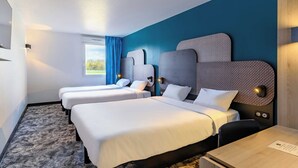 Habitación de hotel con dos camas, un escritorio y un amplio ventanal con cortinas.