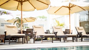 A poolside area with lounge chairs and umbrellas. - Hotel Hazel (Mandalay)