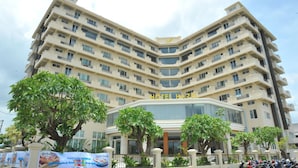 A multi-story hotel with a modern design, featuring balconies on each floor and a prominent entrance with glass doors. - Hotel Hazel (Mandalay)
