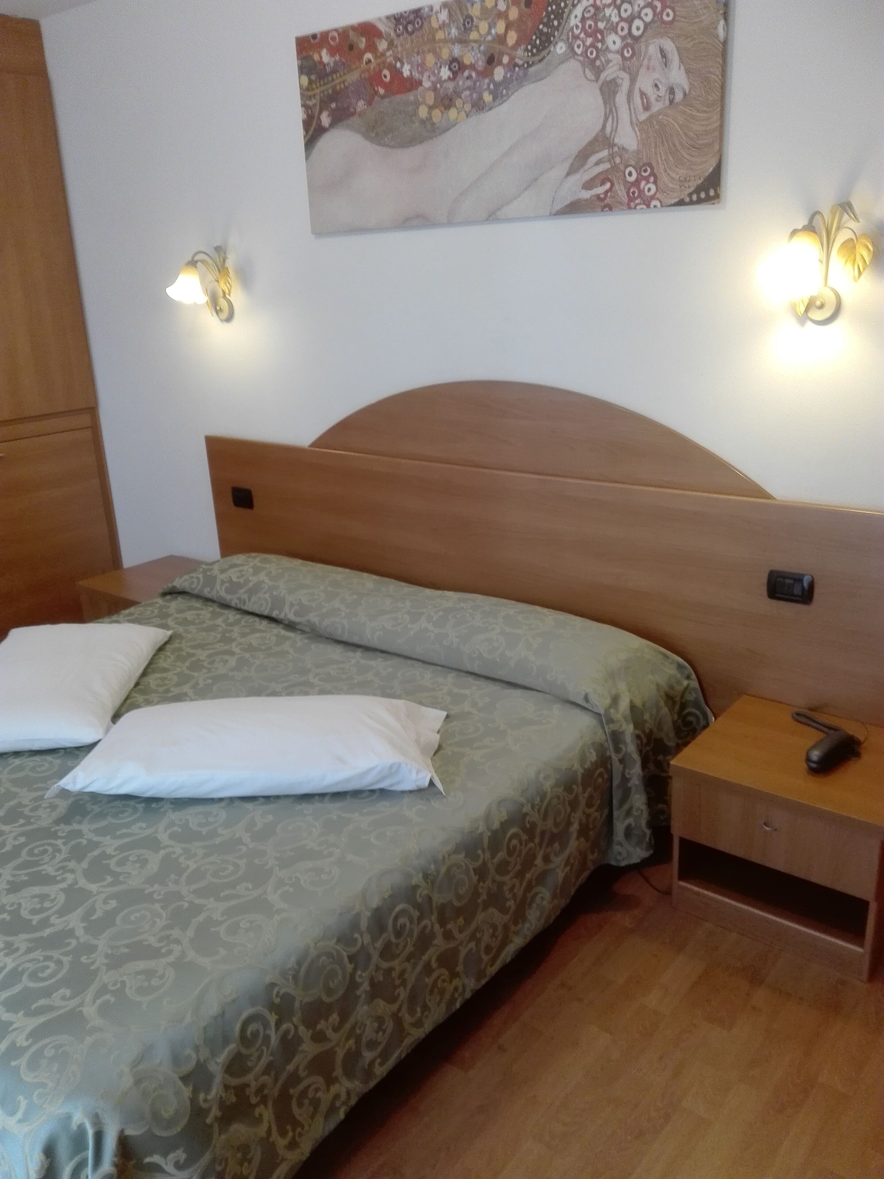 Un lit bien fait, avec une literie à motifs, une tête de lit en bois, des lampes de chevet et une table de chevet avec une télécommande.