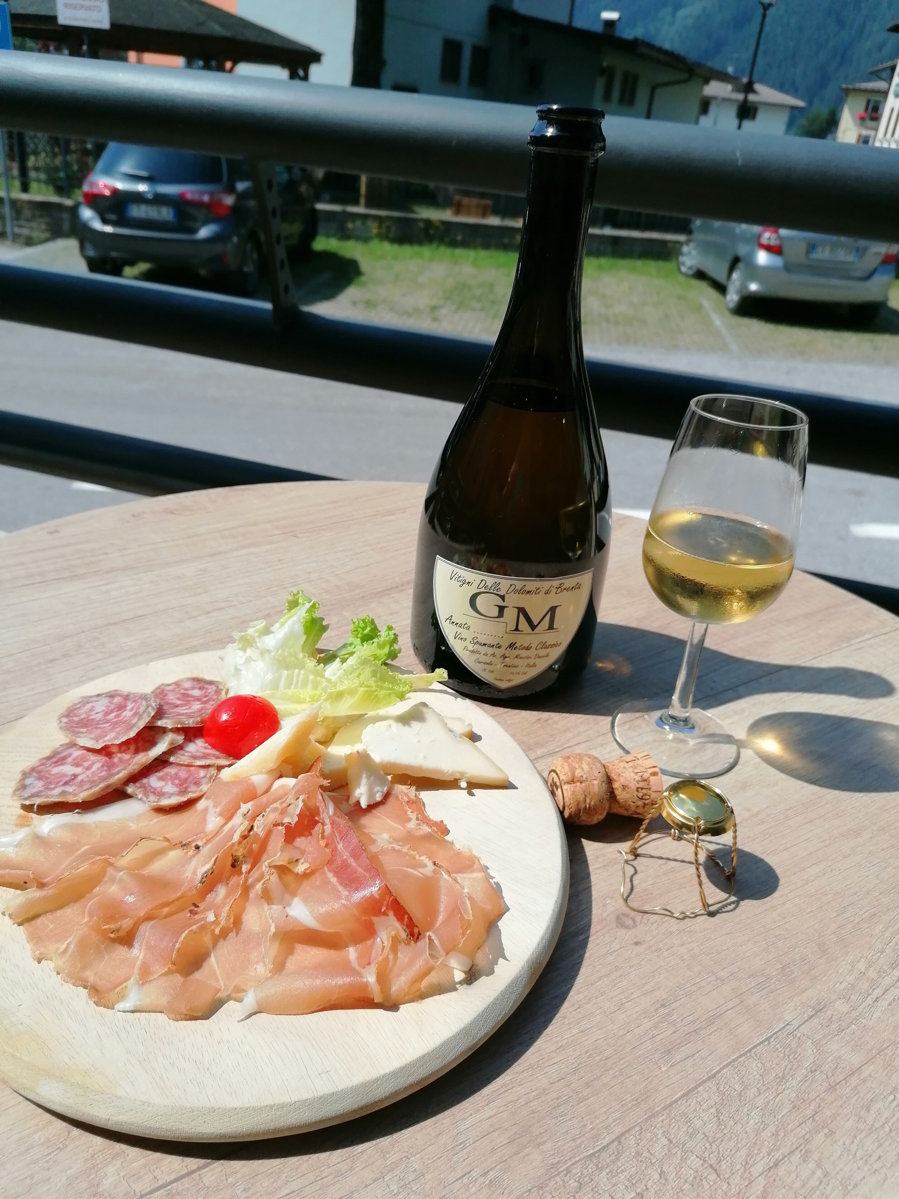 Un tavolo di legno con un piatto di cibo, una bottiglia di vino e un bicchiere di vino.