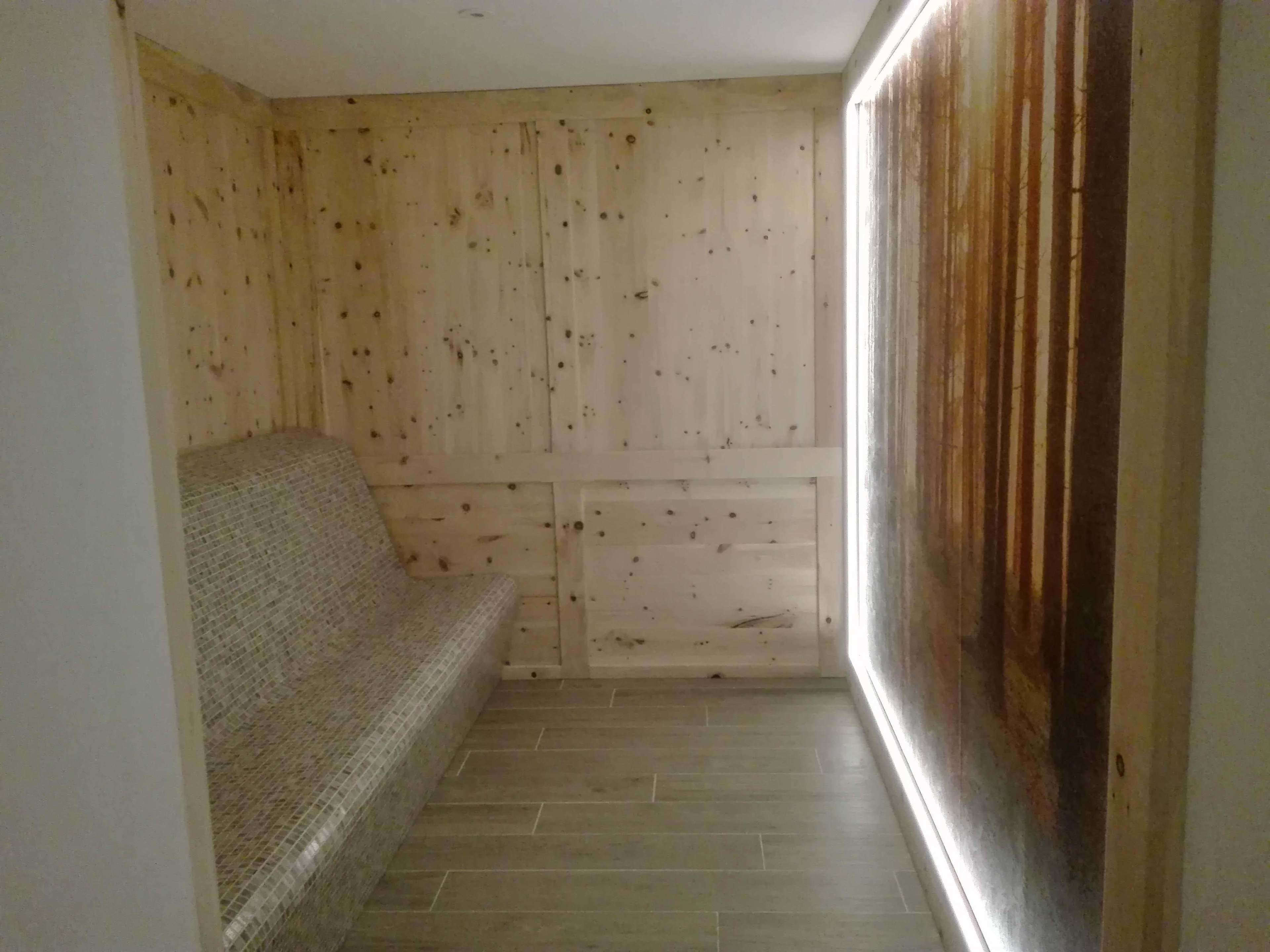 A narrow room with a wooden wall, a tiled floor, and a sofa.
