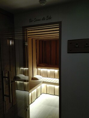 A dimly lit room with a slatted wooden bench and a small bed. - Hotel Denny (Carisolo)