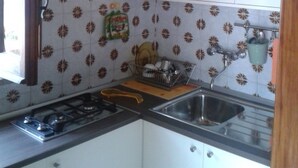 Una cocina con armarios blancos, una estufa a gas, un lavaplatos y azulejos decorativos.
