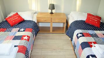 Una habitación con dos camas, cada una con un edredón estampado con motivos de estrellas. Entre las camas, una mesita de noche con una lámpara.