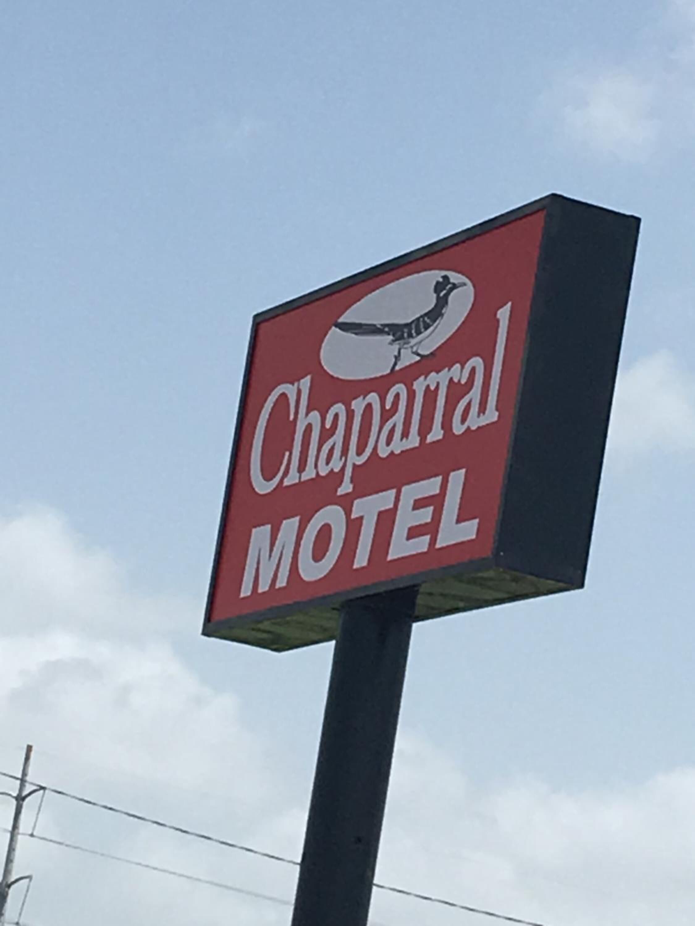 Ein Schild eines Motels mit Vogel-Logo und dem Schriftzug 'Chaparral Motel'.