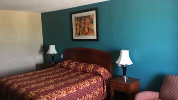 A hotel room with a bed, two bedside tables with lamps, a chair, and a painting on the wall.