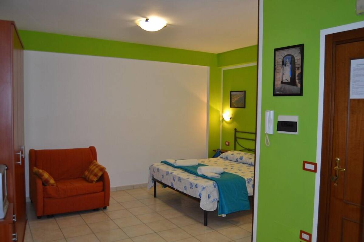 A room with a bed, a chair, and a door.