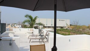 Terraza en la azotea con sillones de descanso y un gran paraguas, con vista a un edificio identificado como 'Liverpool'.