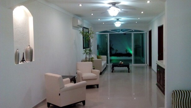 Una sala de estar moderna con sofá, sillones, una mesa de centro y elementos decorativos en las paredes.