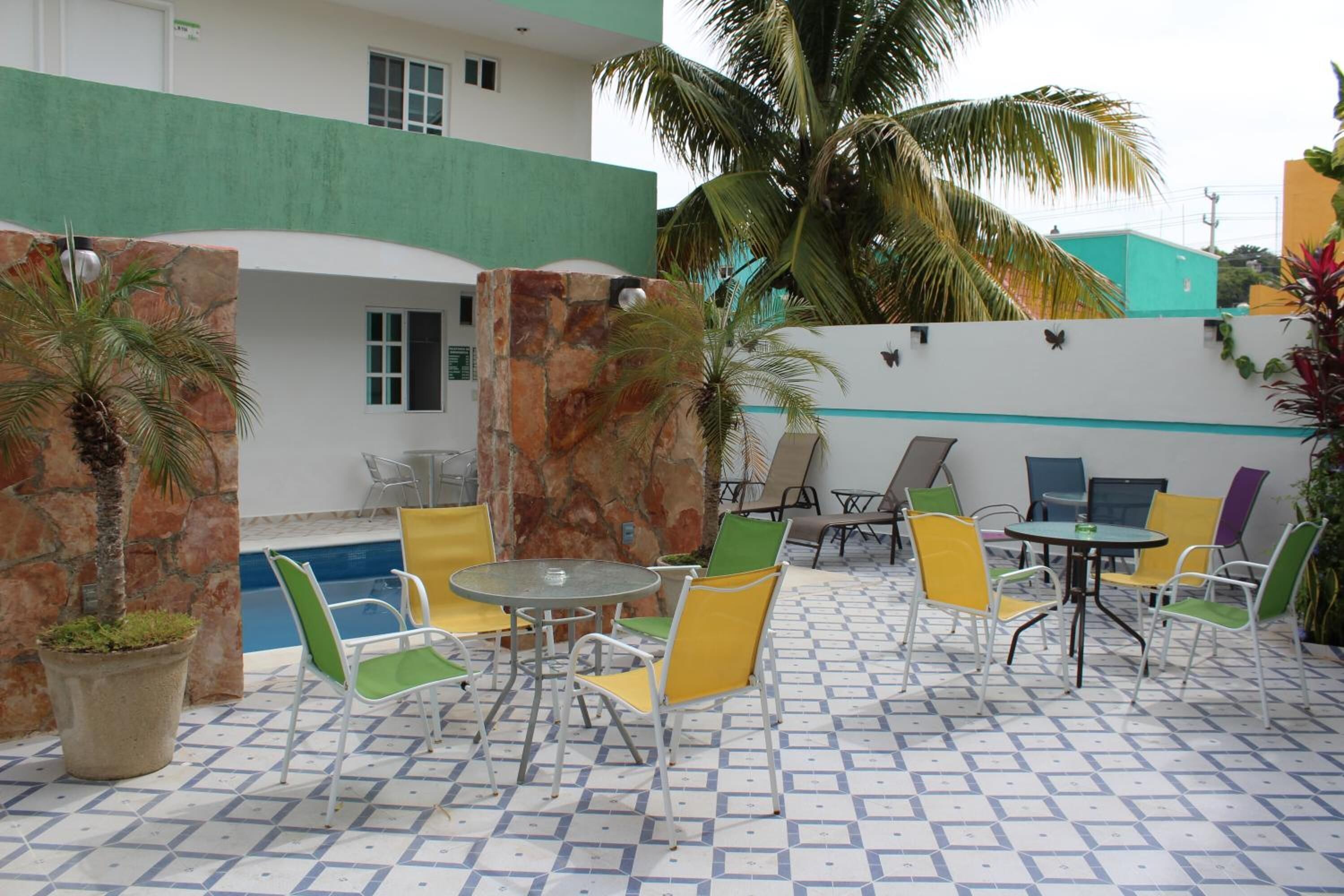 Un patio exterior con piscina, sillas coloridas y un muro de piedra.