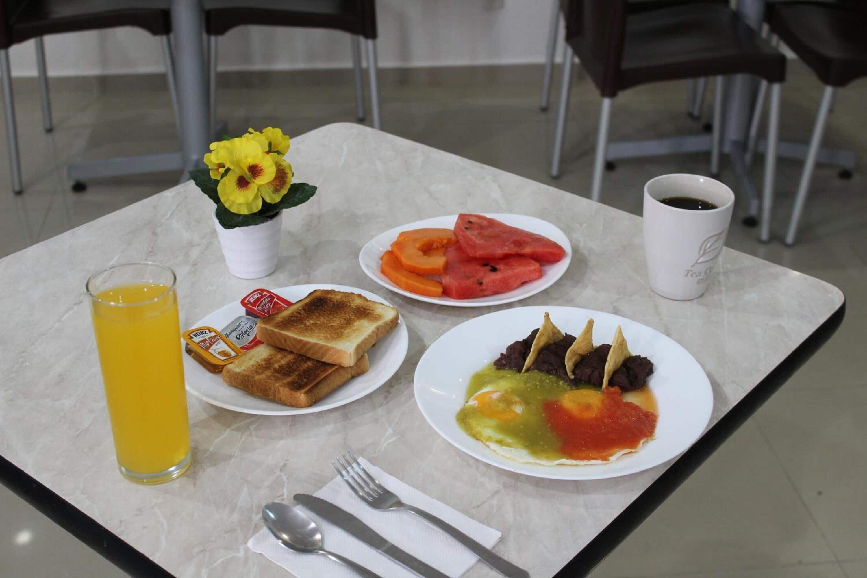 A breakfast table with toast, fruit, and a cup of tea.