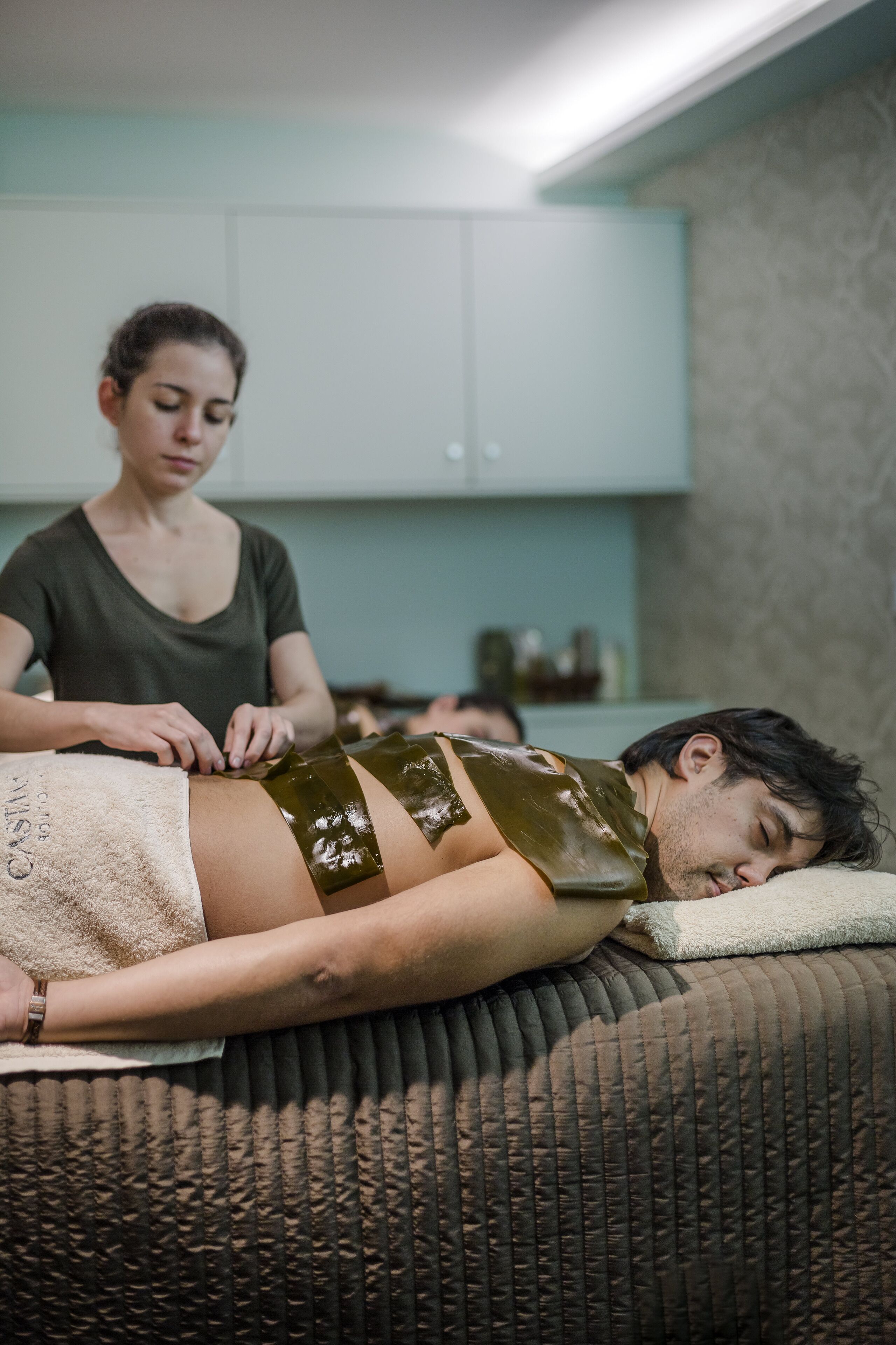 A person lying on a massage table receiving a treatment.