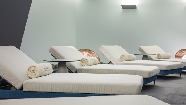 Un área de spa con tres tumbonas, cada una con una toalla y una mesita.