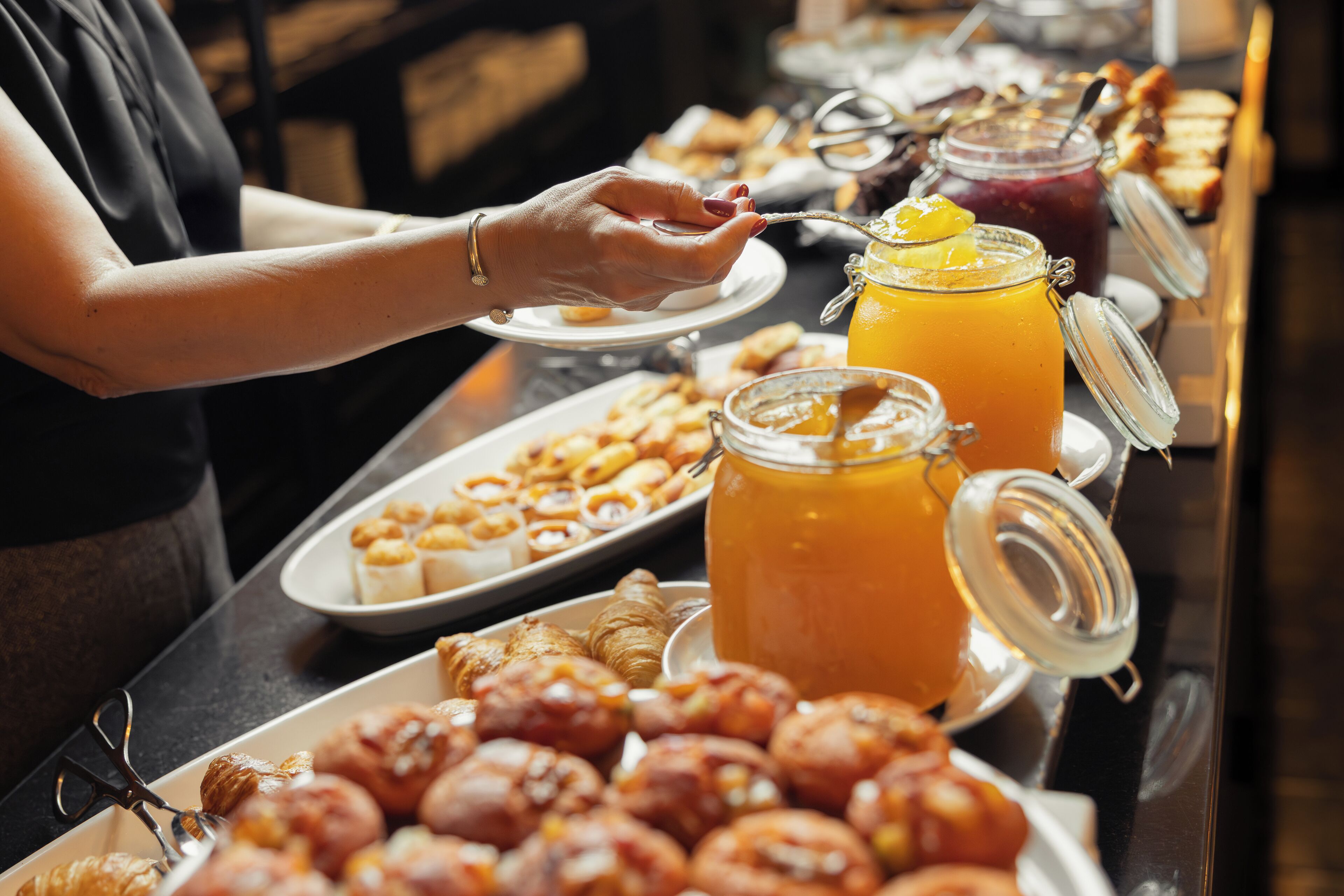 A buffet with various food items and a person serving themselves.