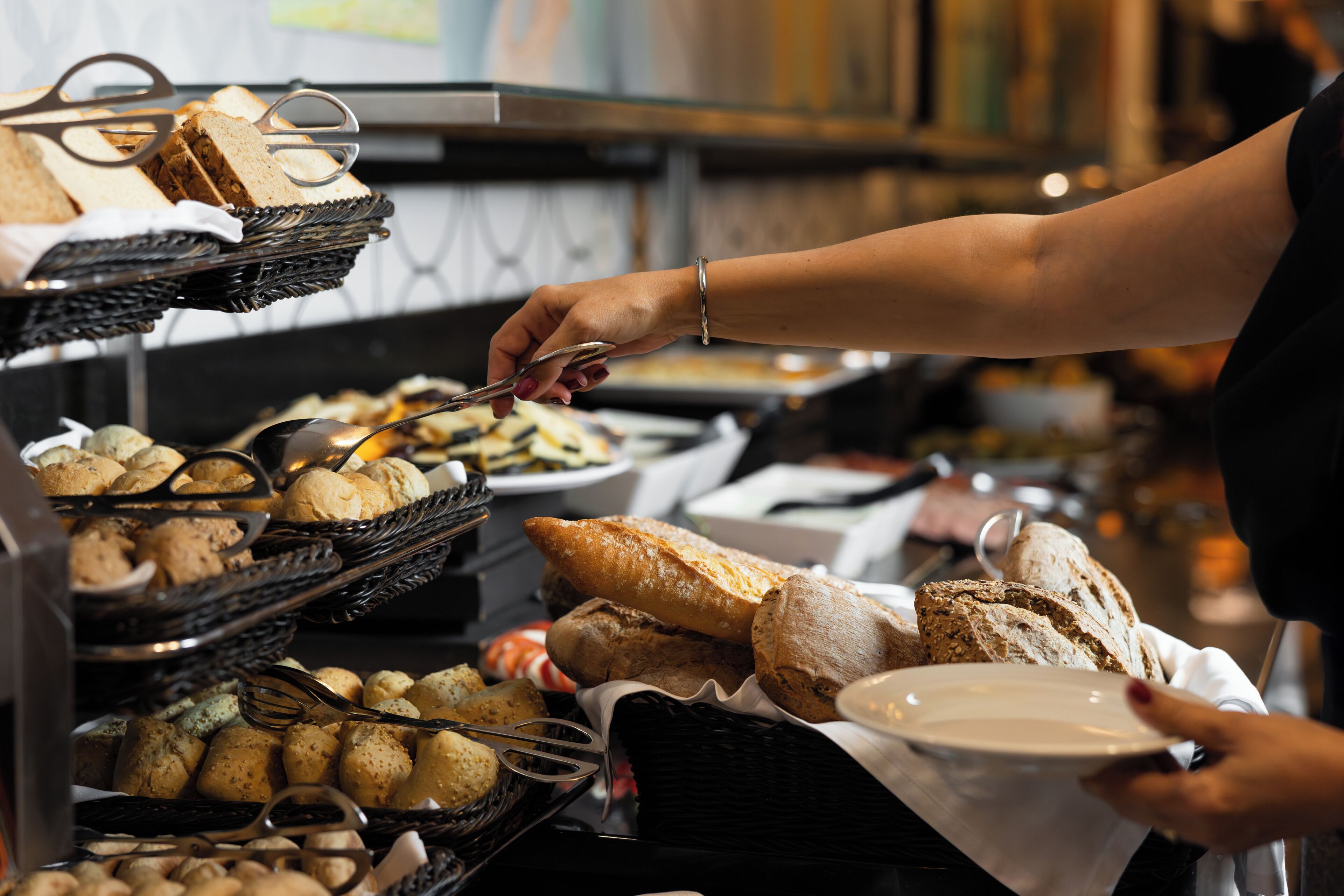 A buffet with various food items, including bread and pastries, being served.