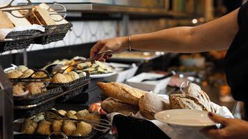A buffet with various food items, including bread and pastries, being served.