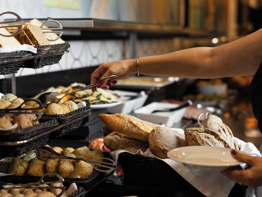 A buffet with various food items, including bread and pastries, being served.