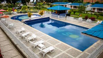 Relax by the pool surrounded by lush greenery and palm trees.
