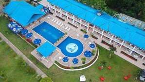 Ett flygbildsbild av ett hotell med en swimmingpool, flera balkonger och utomhusområden med sittplatser.