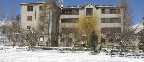 A multi-story building with a stone facade, multiple windows, and a flat roof with solar panels.