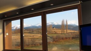 A room with large windows offering a view of a snowy mountain landscape. - Hotel Mirador (Lles)