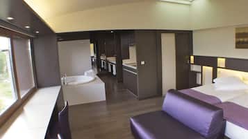 Una habitación de hotel moderna con sofá, cama, una mesita y baño con bañera.