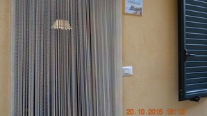 A door with vertical blinds, a light switch, and a small sign on the wall. - Casa Love Marina (Scilla)