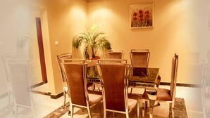 A dining area with a table and chairs, a potted plant, and artwork on the wall. - Beatrice Hotel (Kinshasa)