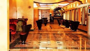 A hotel lobby with a marble floor, red upholstered seating, and a long row of black chairs. - Beatrice Hotel (Kinshasa)