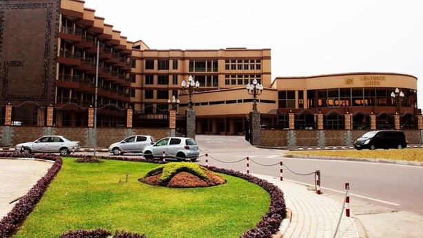 A hotel with multiple floors, a curved building section, and a landscaped garden area. - Beatrice Hotel (Kinshasa)