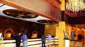 A hotel lobby with a reception desk, a chandelier, and a large potted plant. - Beatrice Hotel (Kinshasa)