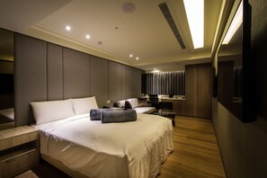 A modern hotel room with a large bed, a desk, and a separate seating area. - FM Hotel (Taichung)