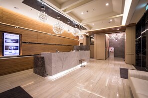 A modern hotel lobby with a reception desk, wooden paneling, and a large chandelier. - FM Hotel (Taichung)