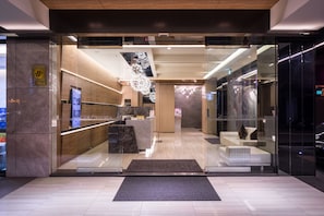 A modern hotel lobby with a reception desk, seating area, and a chandelier. - FM Hotel (Taichung)